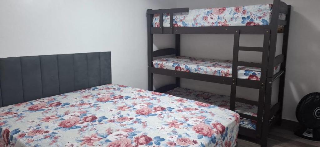 ein Schlafzimmer mit zwei Etagenbetten mit einem Blumenbett in der Unterkunft Casa na praia mongagua próximo da plataforma in Mongaguá