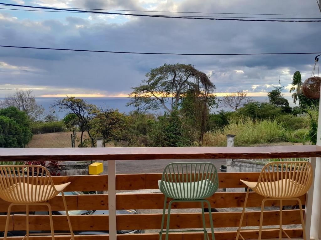 a balcony with two chairs and a view of the ocean at Coucher de soleil in Bouillante
