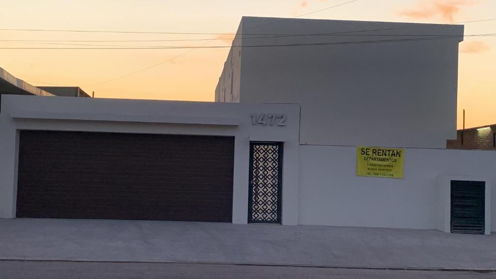 a white building with a garage with a yellow sign on it at Departamentos Yireh in Mexicali