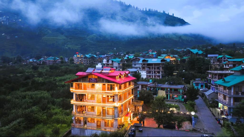 a building in a city with a mountain in the background at WANDER THRIVES INN By Ads Manali in Manāli