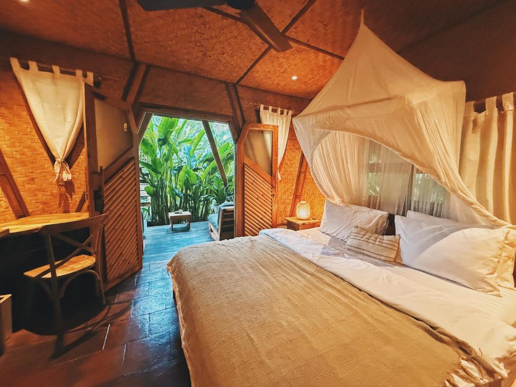 a bedroom with a bed in a room with a window at Batu Kayu Medewi in Medewi