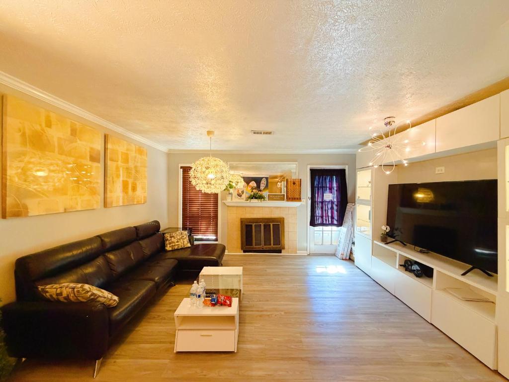 a living room with a black leather couch and a tv at 2 Bedrooms Private Kitchen Livingroom Robinwood Condo Suite in Norcross