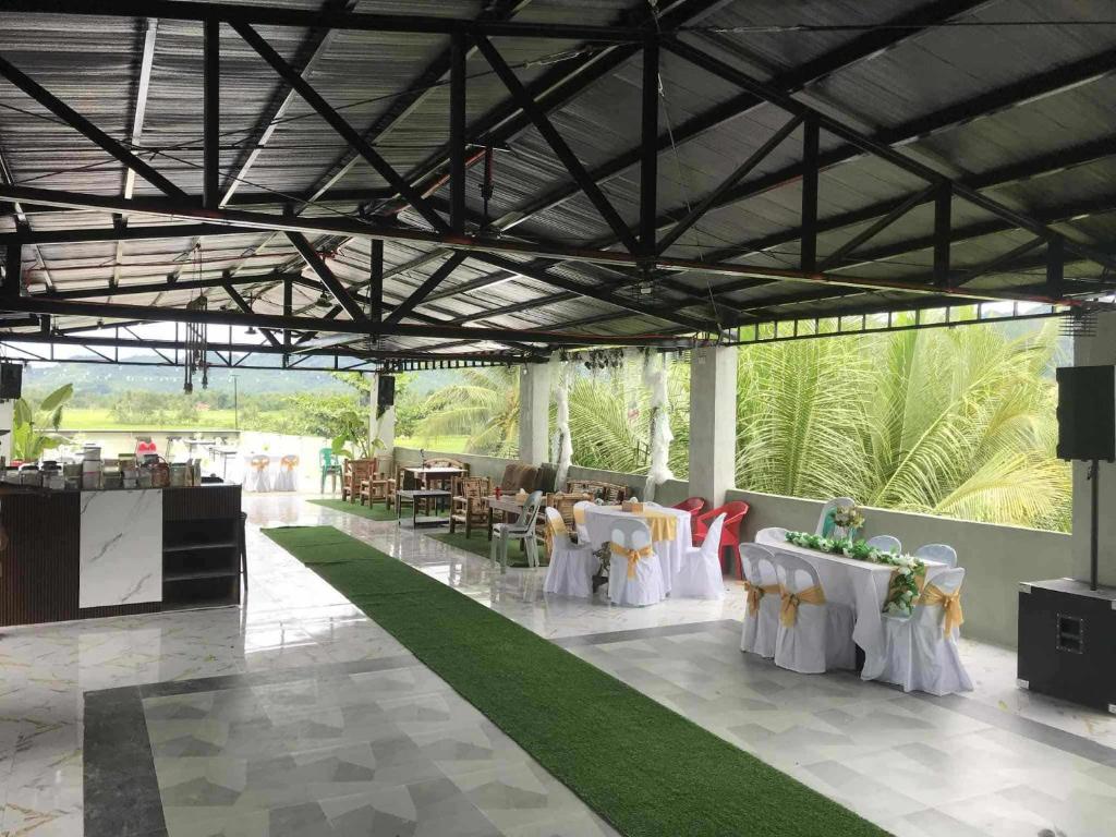 Un salón de banquetes con mesas y sillas blancas y plantas. en American Roadhouse Hotel and Restaurant, en Candijay