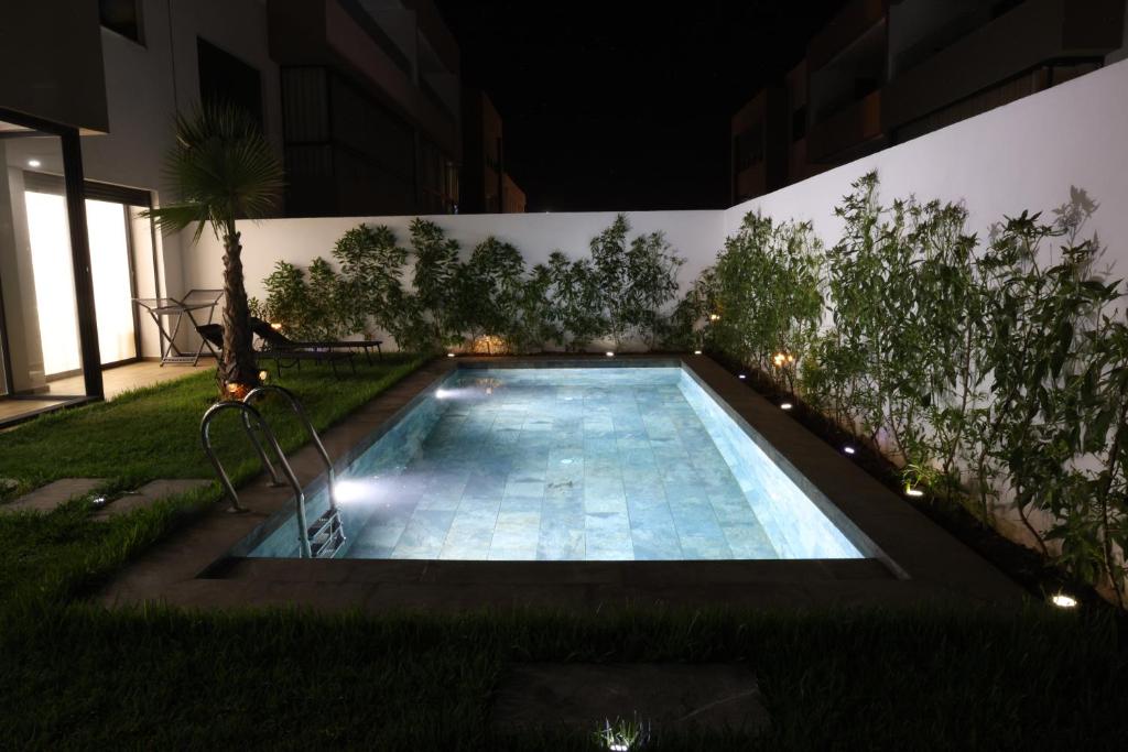 达布阿扎Dar Bouazza Luxury apartment with pools garden sports courts parking near the sea的夜间在院子中间的游泳池