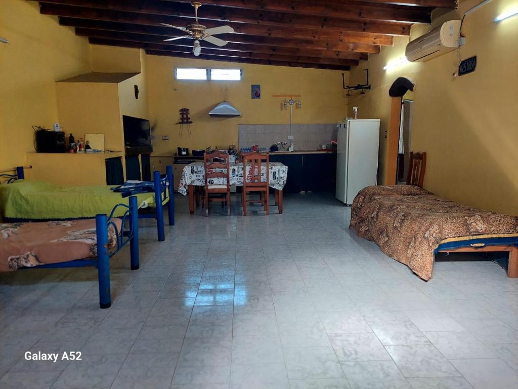 ein Zimmer mit Betten und eine Küche mit einem Tisch in der Unterkunft Depto en arrecifes in Arrecifes