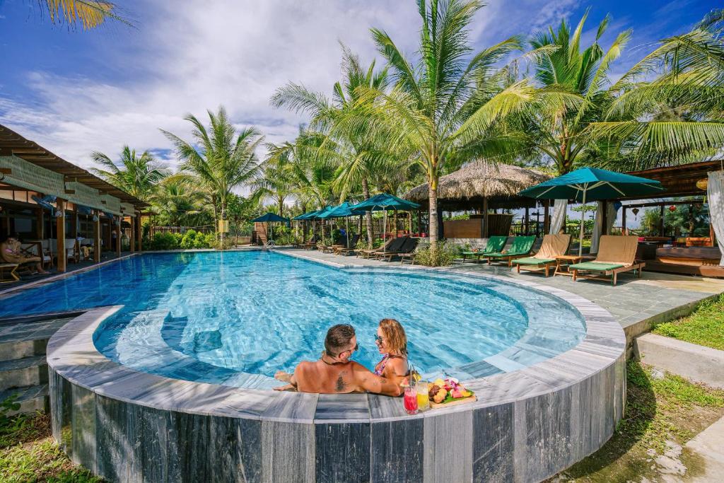 een man en een vrouw zitten in een zwembad bij Hoianbang Beach Front Villa and Restaurant in An Bàn (2)