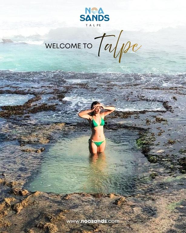 a woman in a bikini standing in the water on the beach at Noa Sands By Ceylon Vistas in Talpe