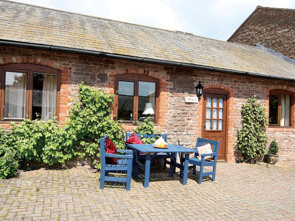 a blue table and chairs in front of a brick building at Bridle Cottage in Hoarwithy