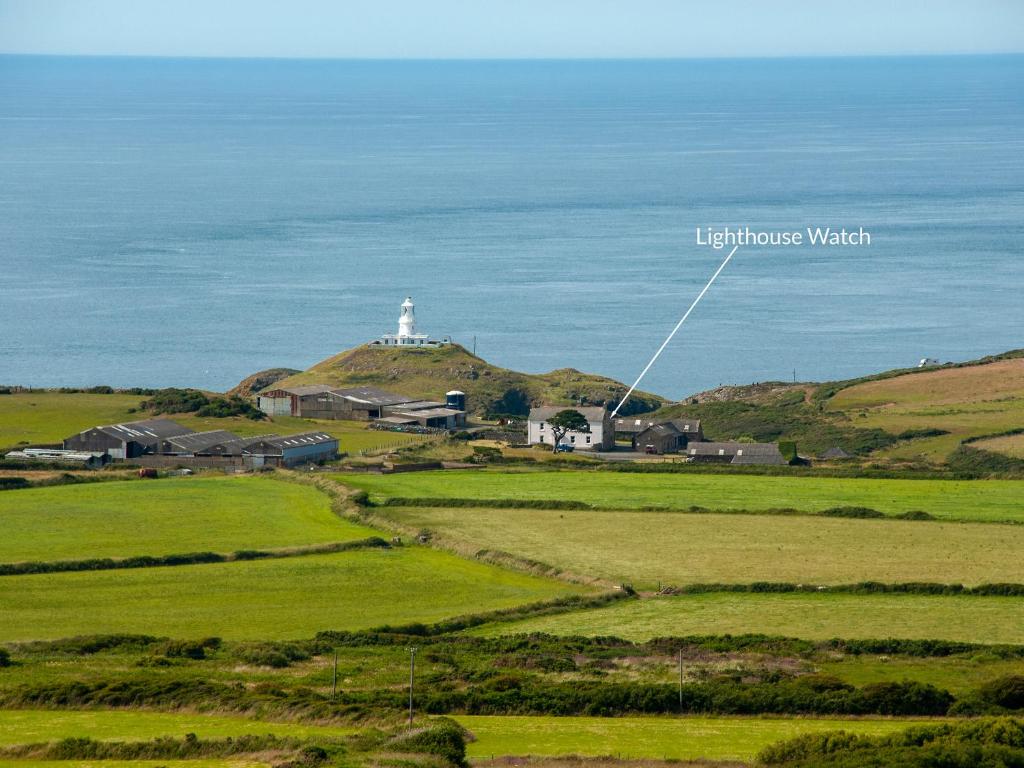 een vuurtoren bovenop een heuvel met een groen veld bij Lighthouse Watch in Saint Nicholas