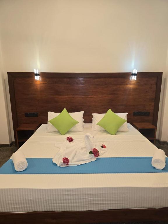 a bed with white sheets and green pillows at Pearl Kingdom Hotel & Resort in Matara