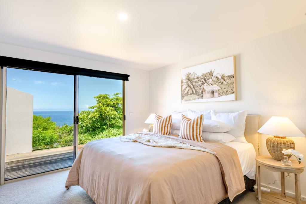 a bedroom with a bed and a large window at Pure Indulgence in Merimbula