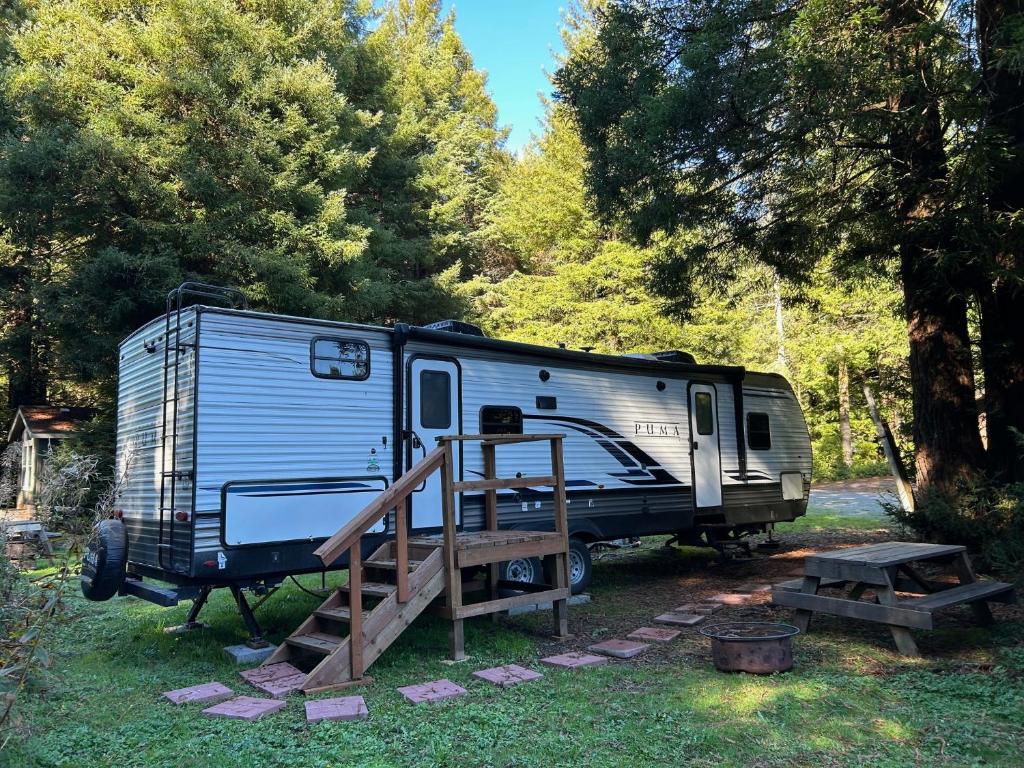 a blue trailer parked in a field with a wooden ramp at Puma The RV in Klamath