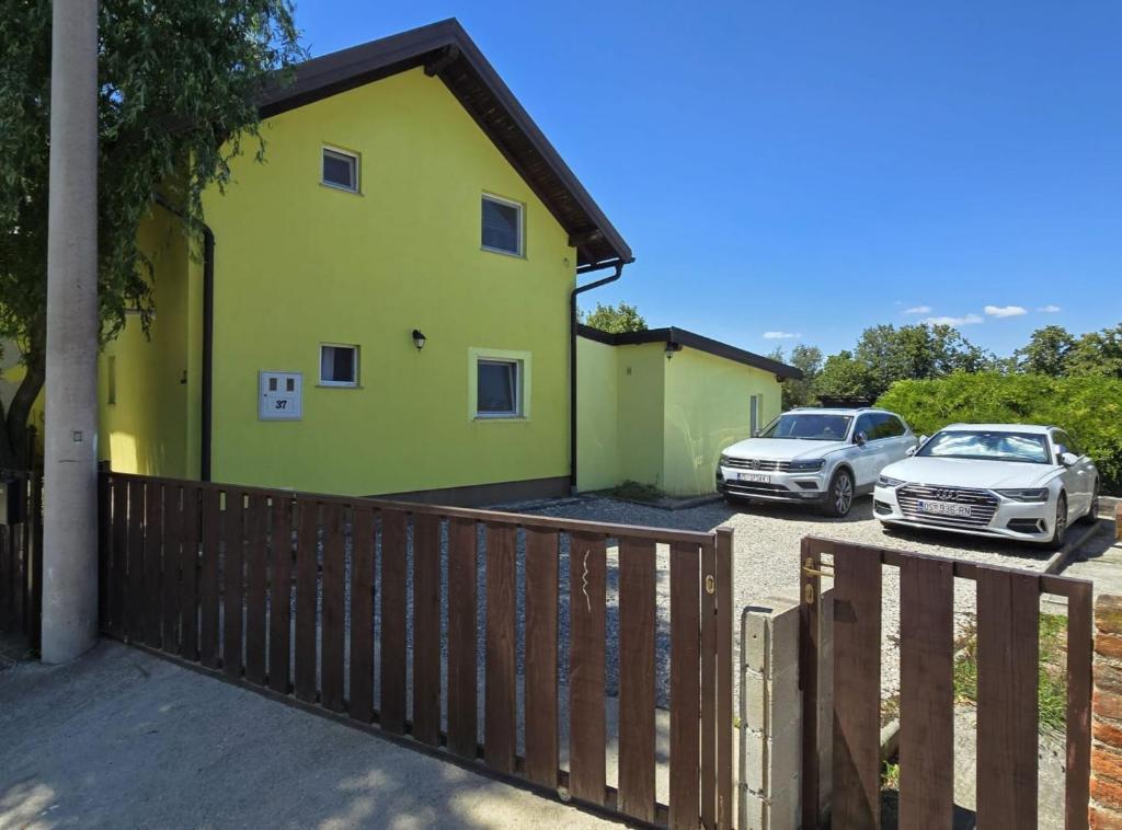 een geel huis met twee auto's geparkeerd op een parkeerplaats bij Luxury Pool Villa Aurora in Hrebinec