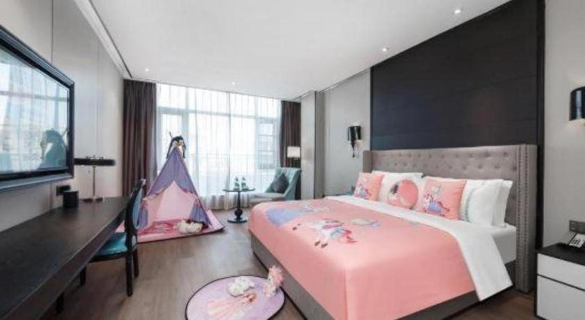 een slaapkamer met een groot roze bed met een bureau en een ladekast bij Xana Hotelle Luzhou High-Speed Railway Station Trading Market Passenger Terminal in Luzhou