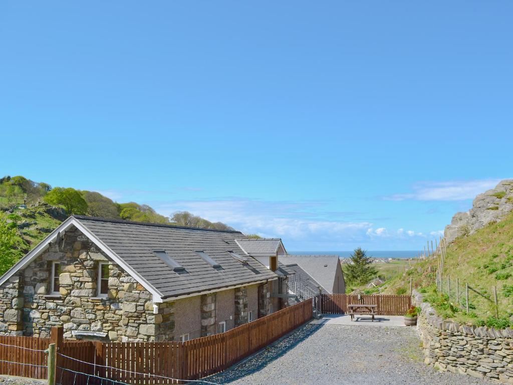 an old stone house with a fence around it at Ysgubor Uchaf - 29517 in Fairbourne