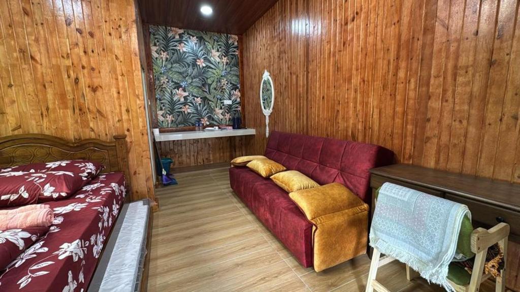 a living room with a red couch and wooden walls at D'Kebun Lenggong Perak Chalet in Gua Sai