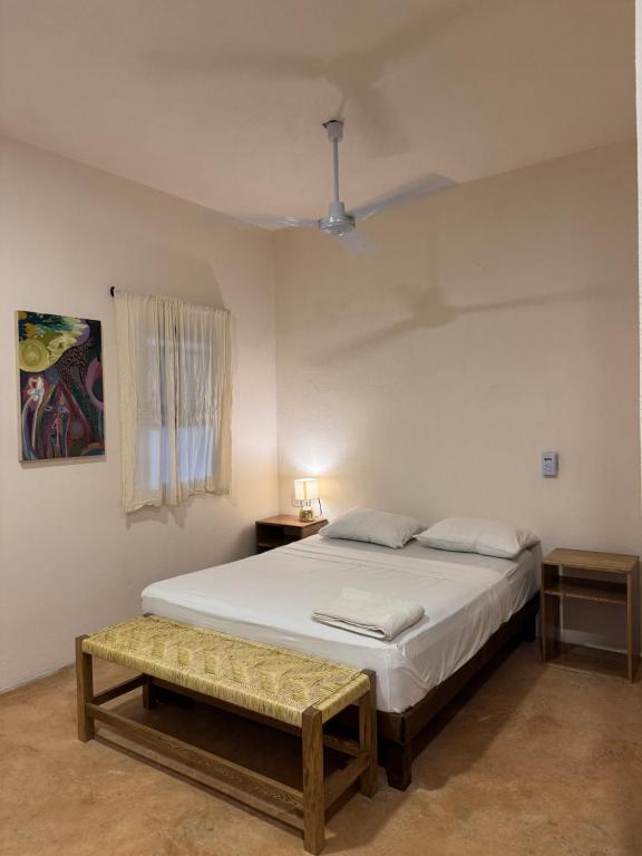 ein Schlafzimmer mit einem weißen Bett und einer Bank in der Unterkunft la punta surf house 2 in Brisas de Zicatela
