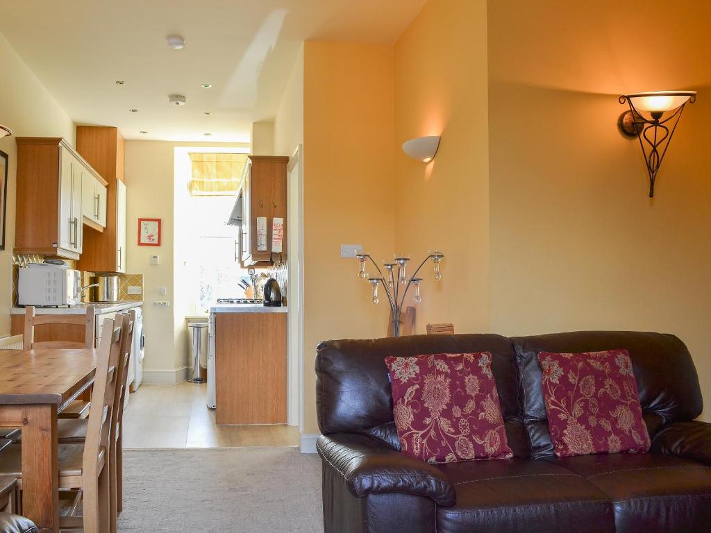 a living room with a leather couch and a kitchen at Fell View in Ambleside