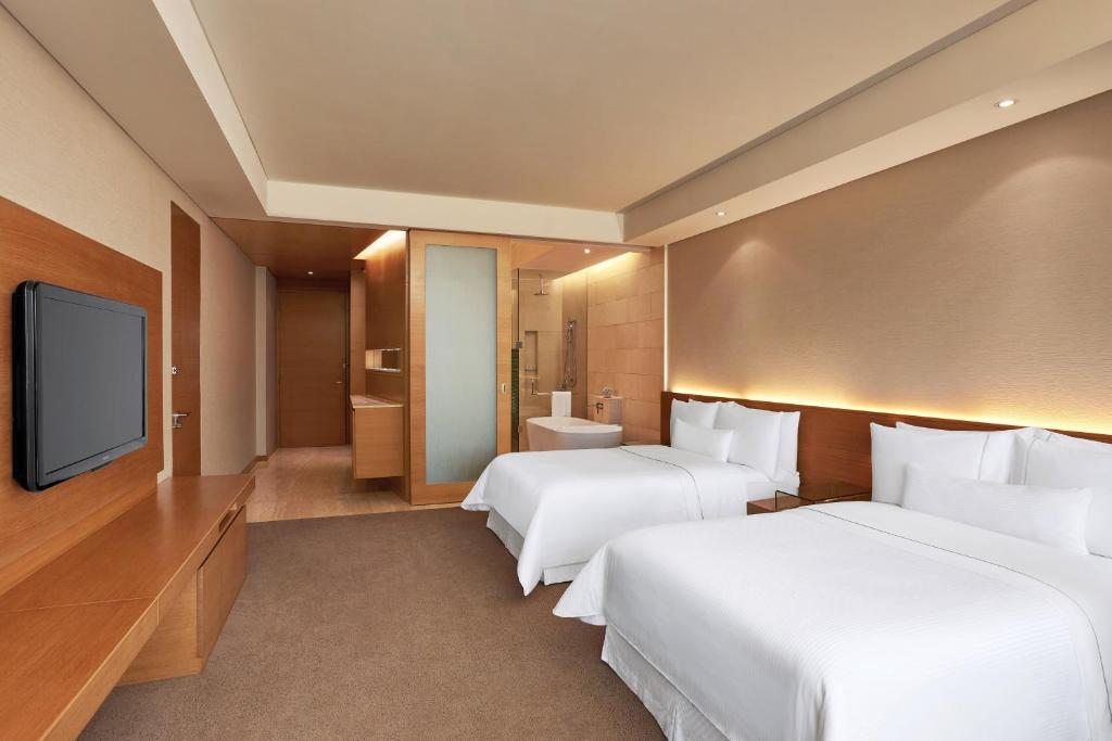 una habitación de hotel con dos camas y un televisor de pantalla plana en The Westin Mumbai Garden City, en Bombay