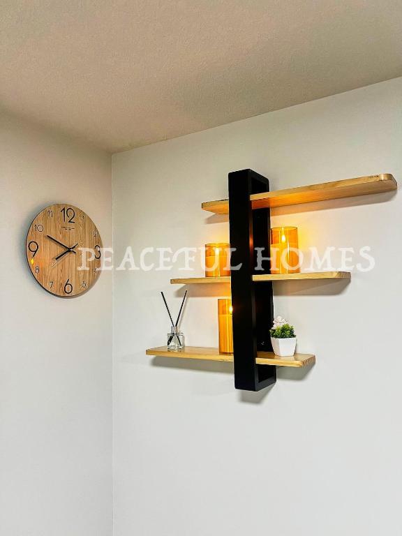 a clock on a wall next to a shelf at Peaceful Homes - Elegant 2 Bedroom Suite in Calgary