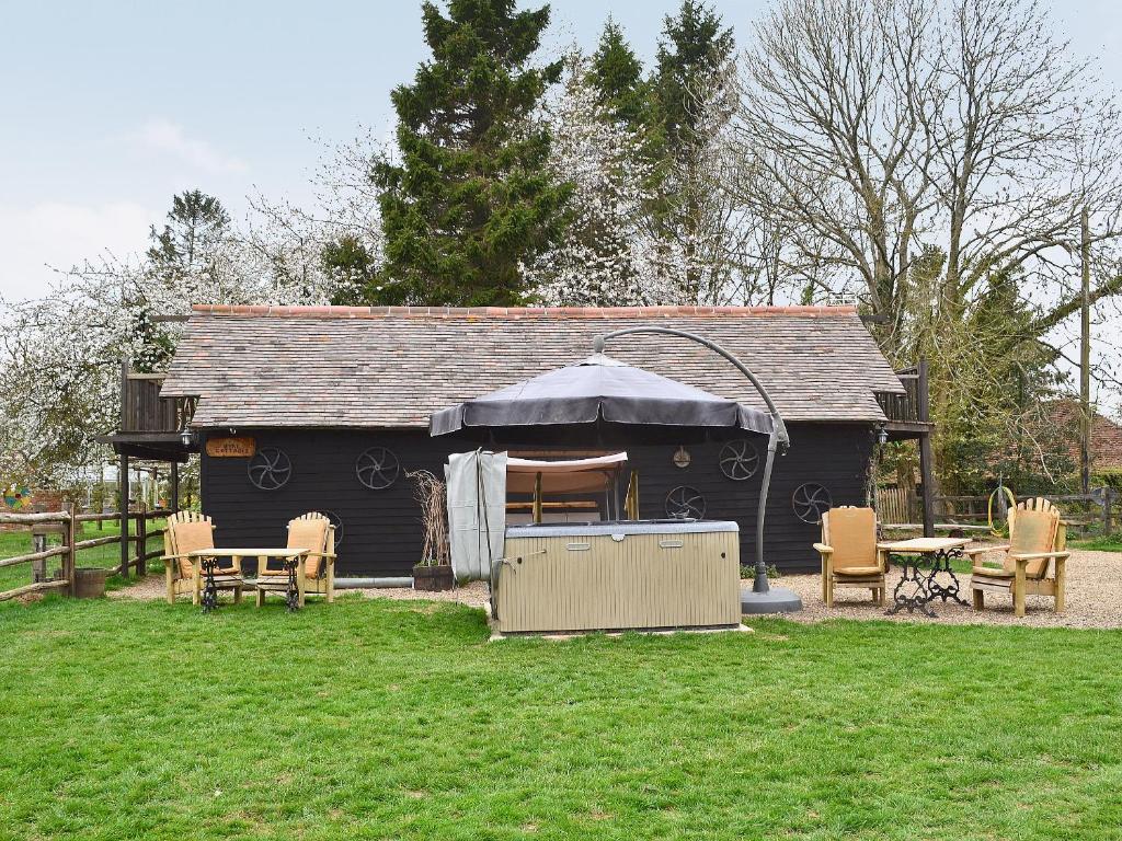 a black shed with a table and chairs in a yard at Robins Nest - 29409 in Elmsted
