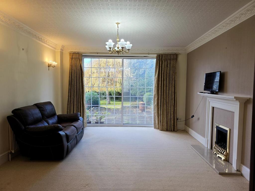 un salon avec un canapé et une grande fenêtre dans l'établissement 3 Bedroom whole house with free car parking, à Leicester