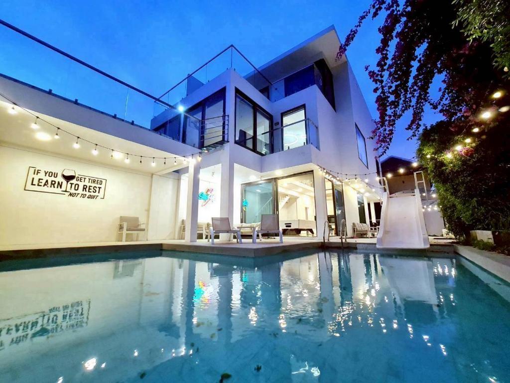 a house with a swimming pool in front of it at ปาล์มสปริง by Nimo villa pattaya in Ban Nong Pru