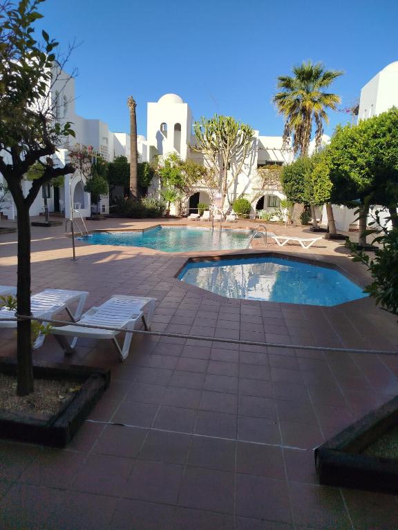 a swimming pool with two lounge chairs and a tree at TorrelagunaVera in Palomares
