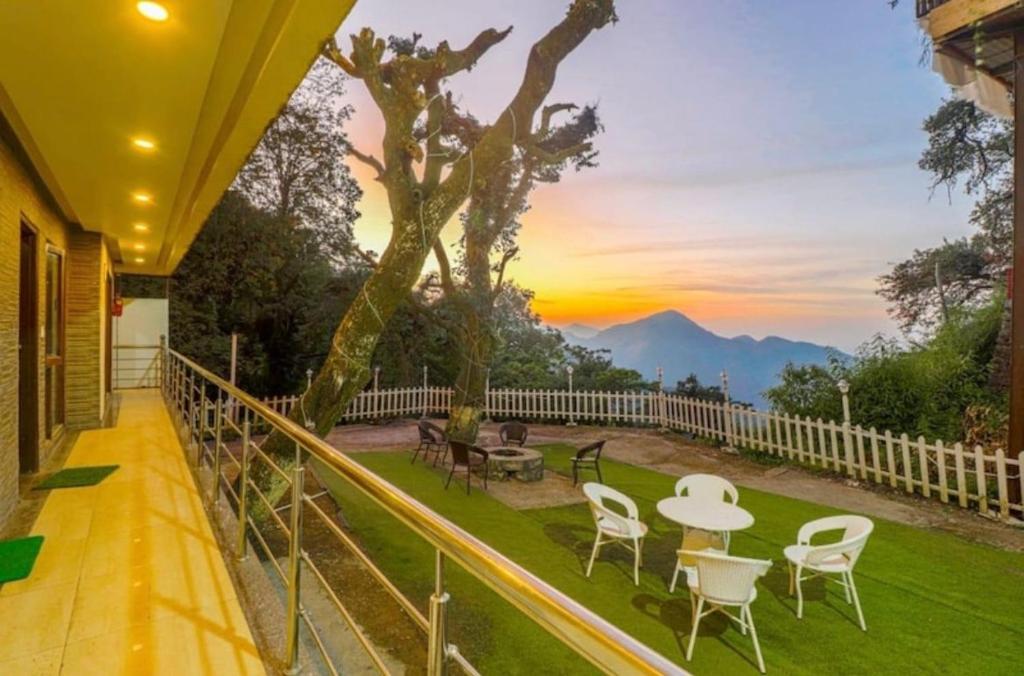 einen Balkon mit einem Tisch und Stühlen sowie einem Sonnenuntergang in der Unterkunft Bentenwood Cottage - A Beautiful Boutique Cottage away from city hustle in Manali