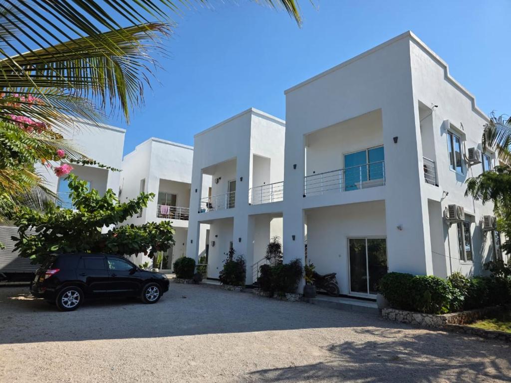 een auto geparkeerd voor een wit gebouw bij Active Apartments in Paje