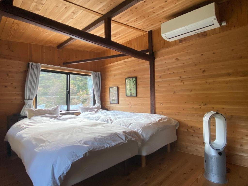 a bedroom with a bed in a wooden room at Sakura House サクラハウス 高知駅から車で20分-豊かな自然を味わう山の隠れ家 in Kochi