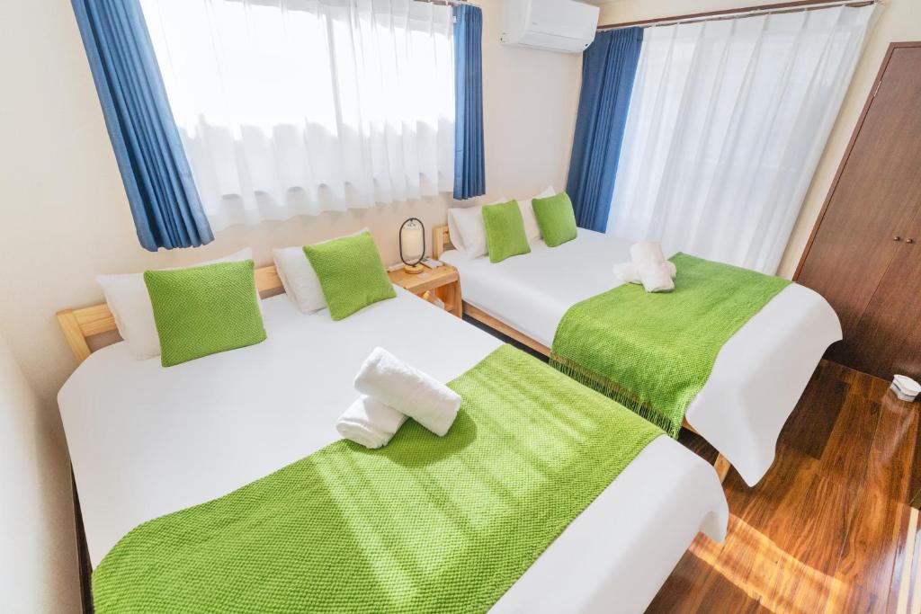 two beds in a room with green and white at 202 Room, a 6-minute walk from Tokyo Koiwa Station Direct connected to Shinjuku and Akihabara Stations Comfortable one-bedroom apartment with separate wet and dry areas in Tokyo