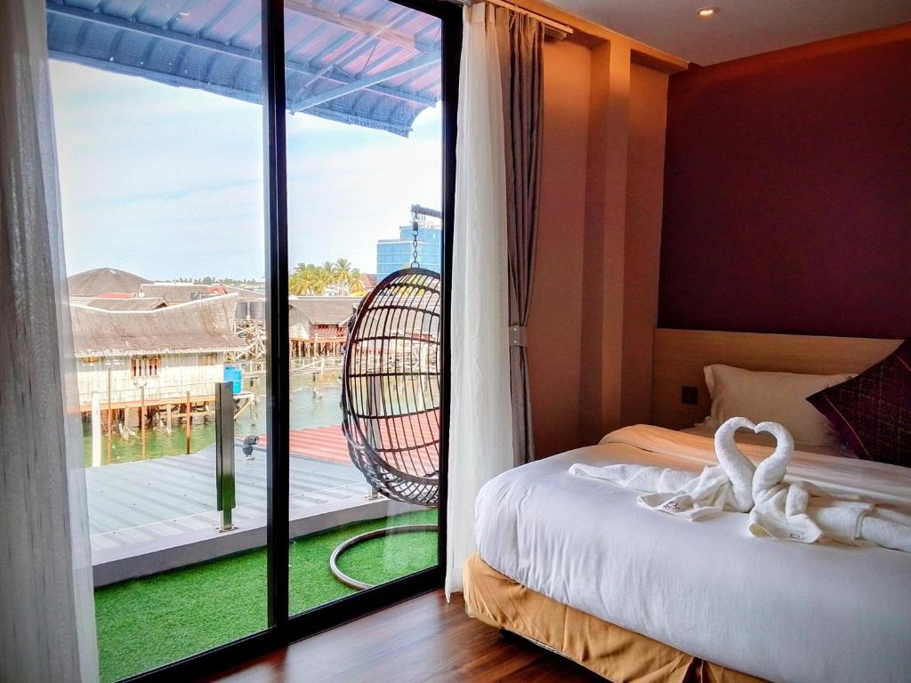 a room with a bed and a balcony with a view at Q3 Inn in Semporna