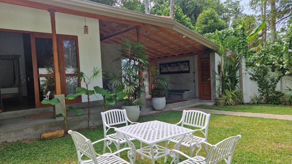 a white table and chairs in a yard at Villa Bell Rose Hikkaduwa in Hikkaduwa