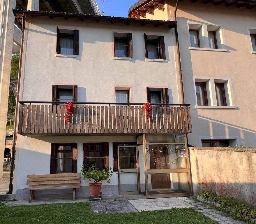 Conveniente, tranquilla con parcheggio في بيلونو: مبنى مع شرفة عليها زهور حمراء