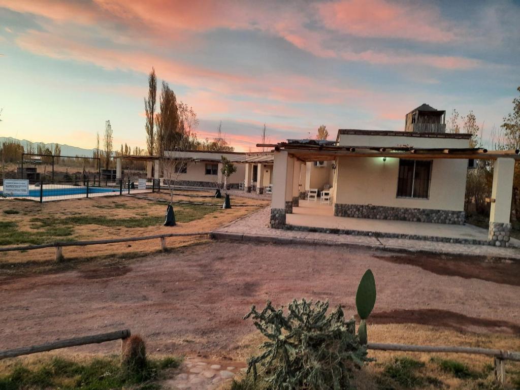 a house in a field with a sunset in the background at El Mirador A Los Andes in Barreal