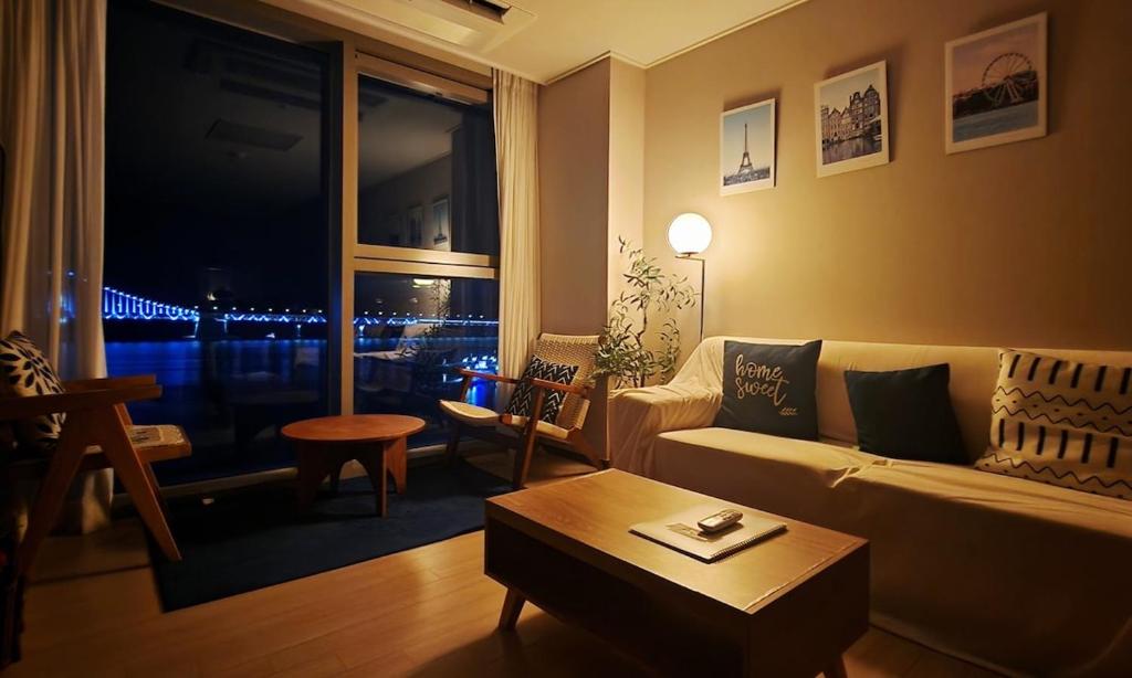 a living room with a couch and a table and a window at an emotional view of the sea at sunrise in Kwangan-dong