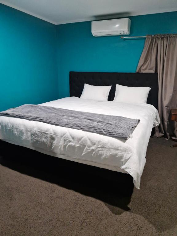 une chambre avec un grand lit avec un mur bleu dans l'établissement Master bedroom, à Tauranga