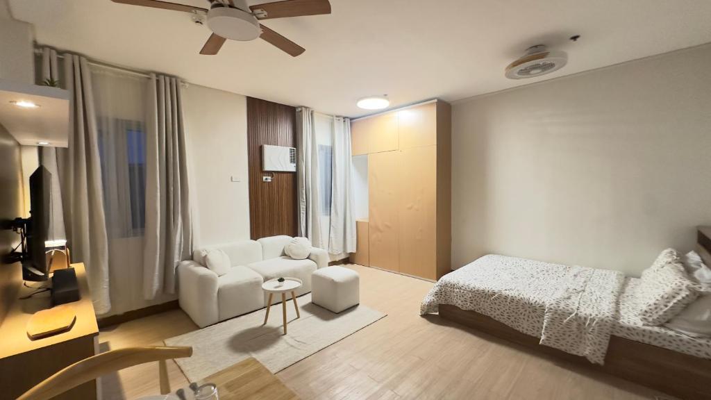 a bedroom with a bed and a couch and a chair at Resort Condo in Trece Martires Cavite in Trece Martires