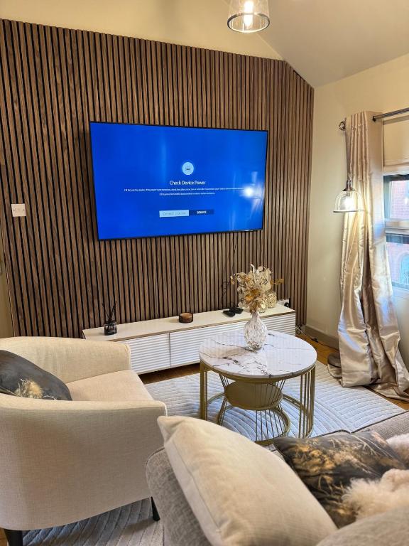 a living room with a large tv on a wall at Hayloft studio apartment in Warwick