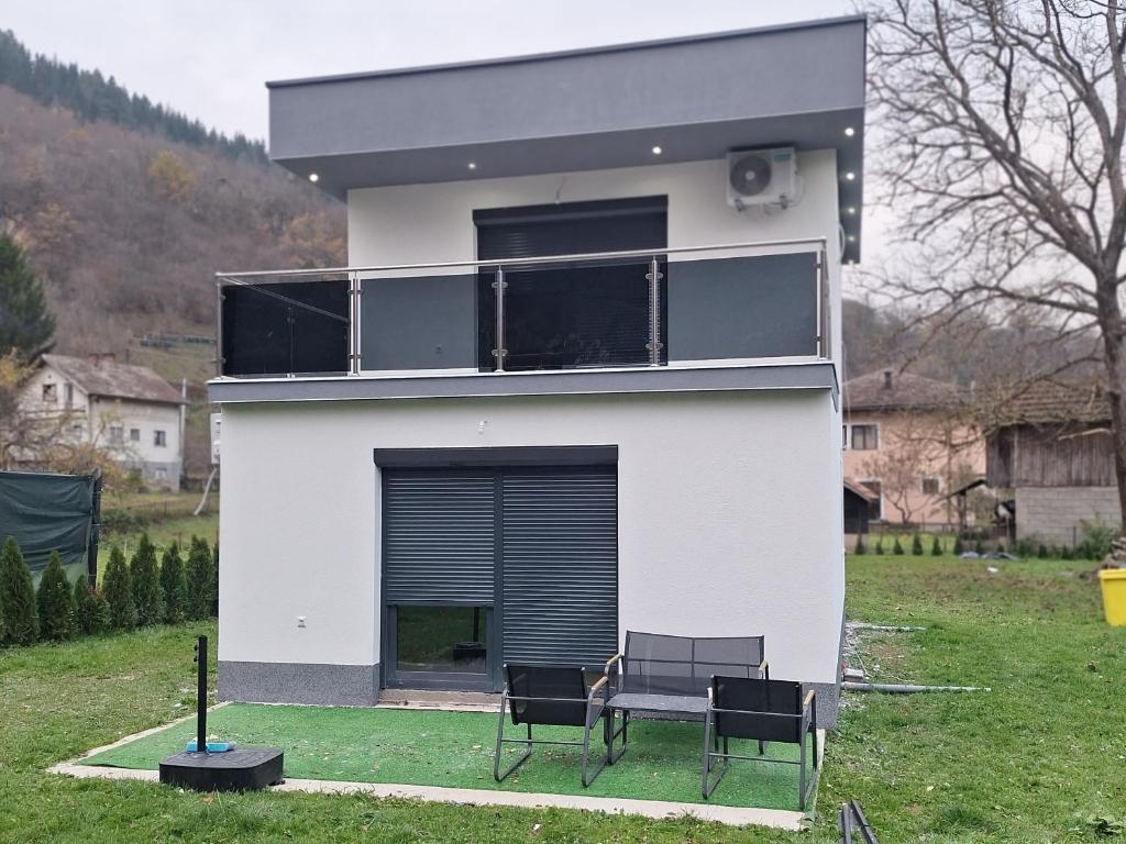 una casa blanca con un perro sentado en un banco en Oaza mira 2, en Jajce