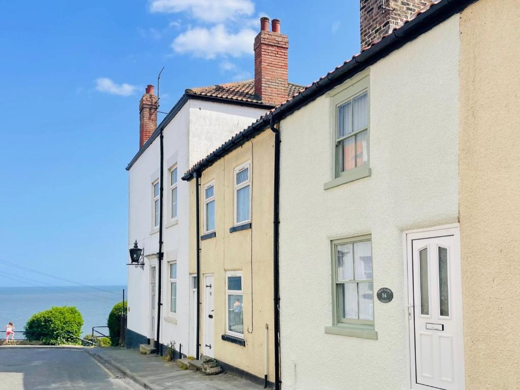 a row of houses on a street next to the ocean at Billy Napp's Cottage in Filey