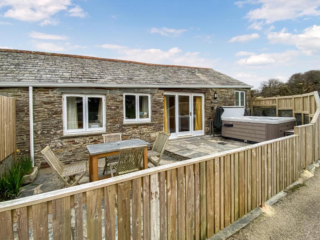 a cottage with a wooden fence and a patio at Wild Rose in Delabole