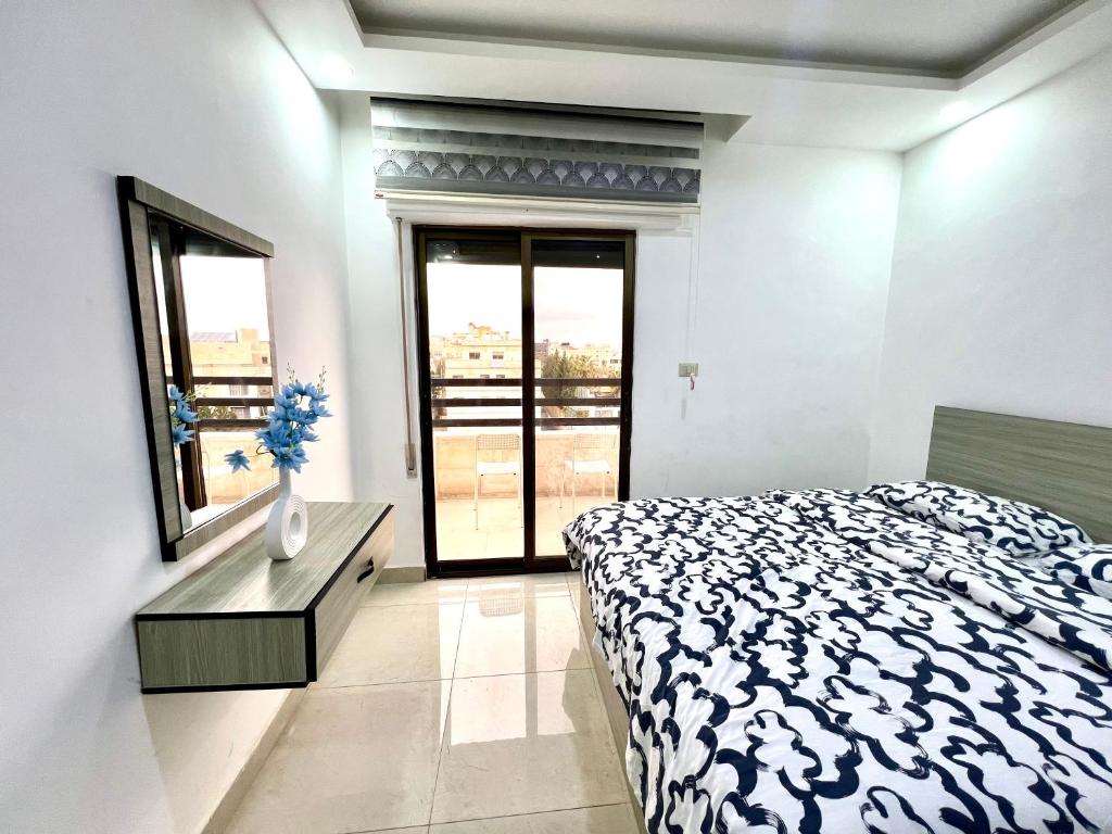 a bedroom with a bed and a vase with flowers in it at Ammon Sun Residence in Amman