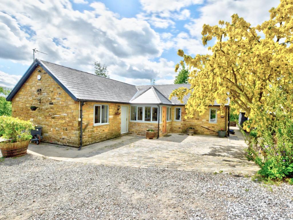 a stone house with a driveway in front of it at Hadrians Garden Villa in Bardon Mill
