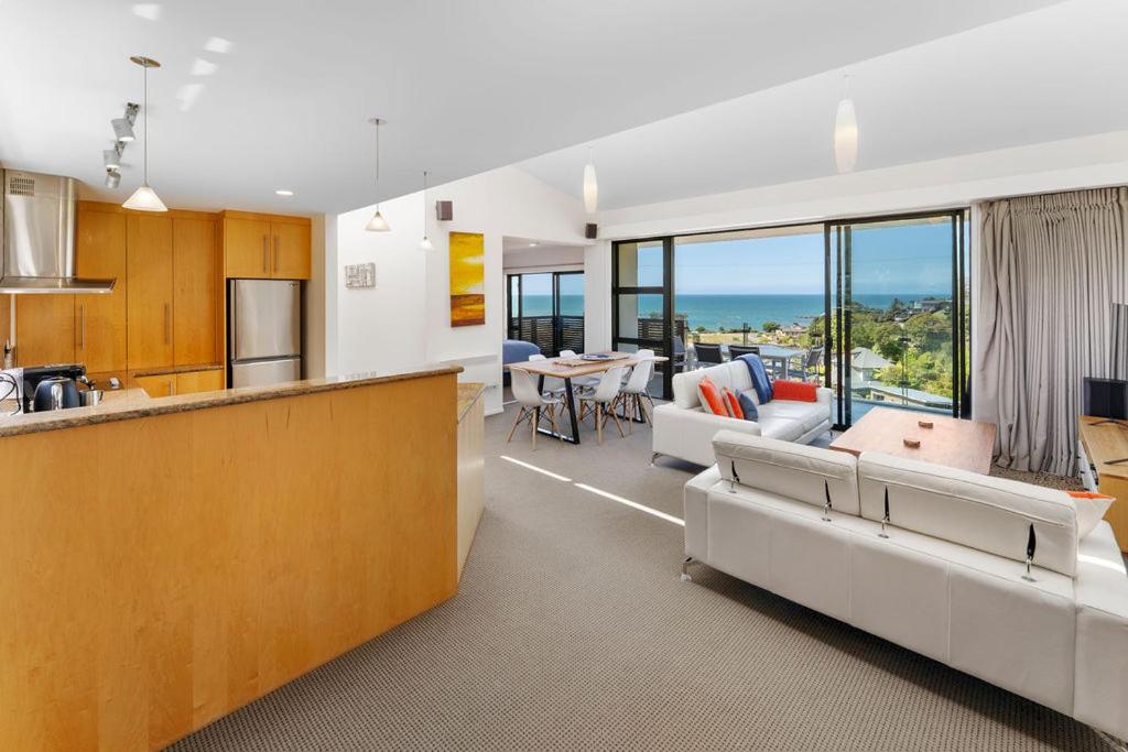 an open kitchen and living room with a view of the ocean at Kaiteriteri Luxury Apartment in Kaiteriteri