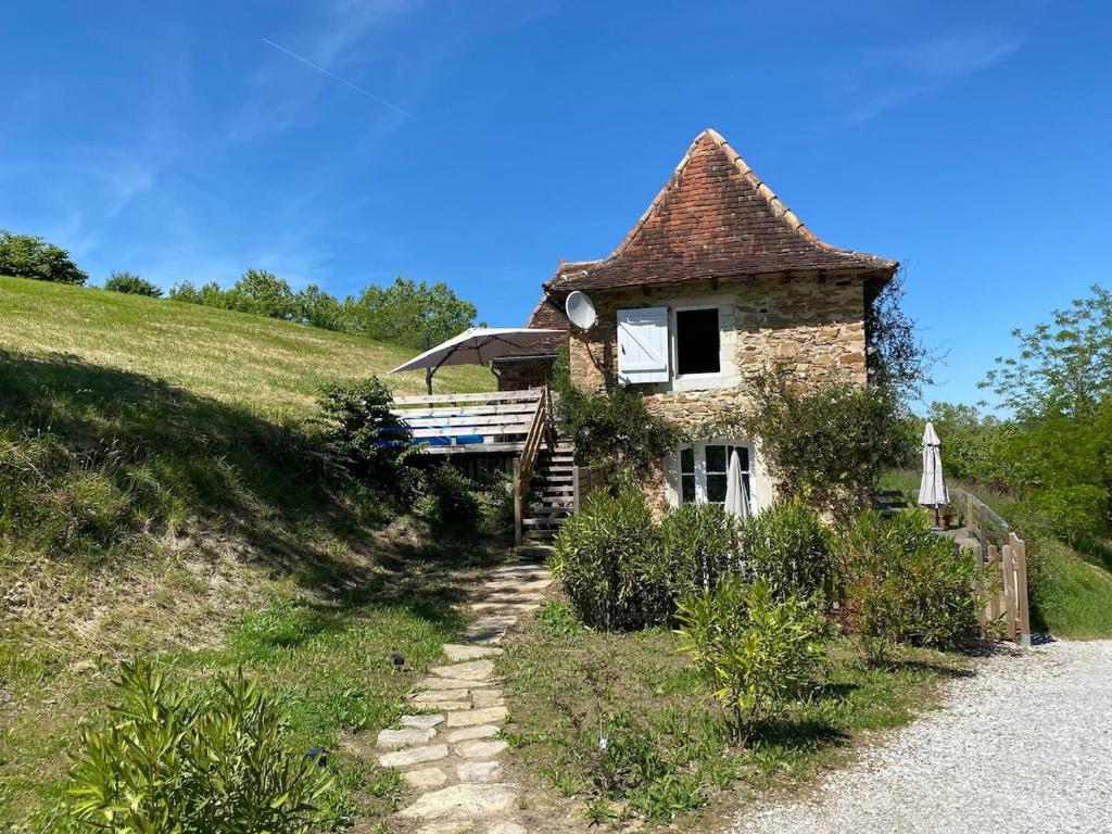 a small stone house on a hill next to a road at la cachette bas in Salies-de-Béarn