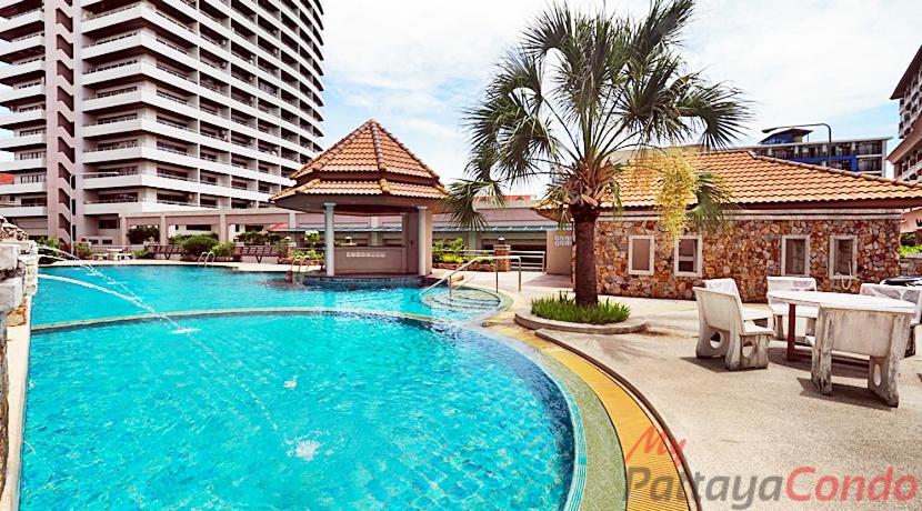 a swimming pool with a table and chairs and a building at Pattaya Center Point Condo in Pattaya
