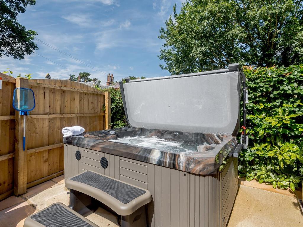 a large hot tub in a yard with a chair at The Chicken Coop in Fulletby