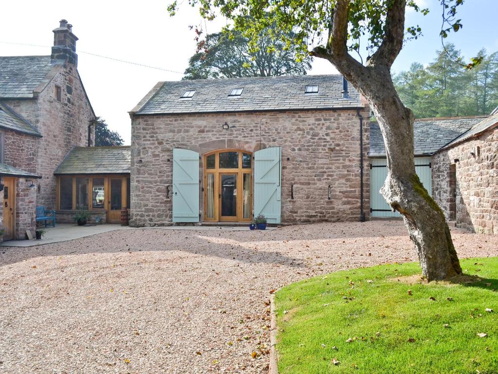 an old brick house with a tree in front of it at The Barn in Greystoke